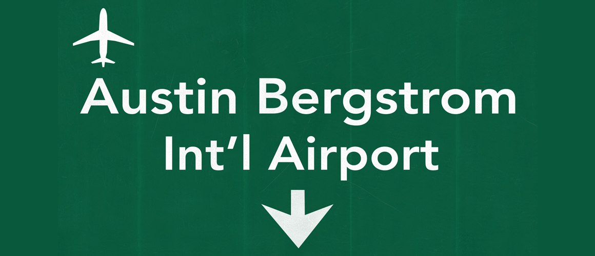 Road sign pointing straight ahead toward Austin-Bergstrom International airport.