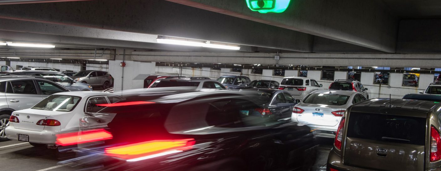 A close-up of a car parking under a Park Assist camera based M5 smart sensor in a parking garage.