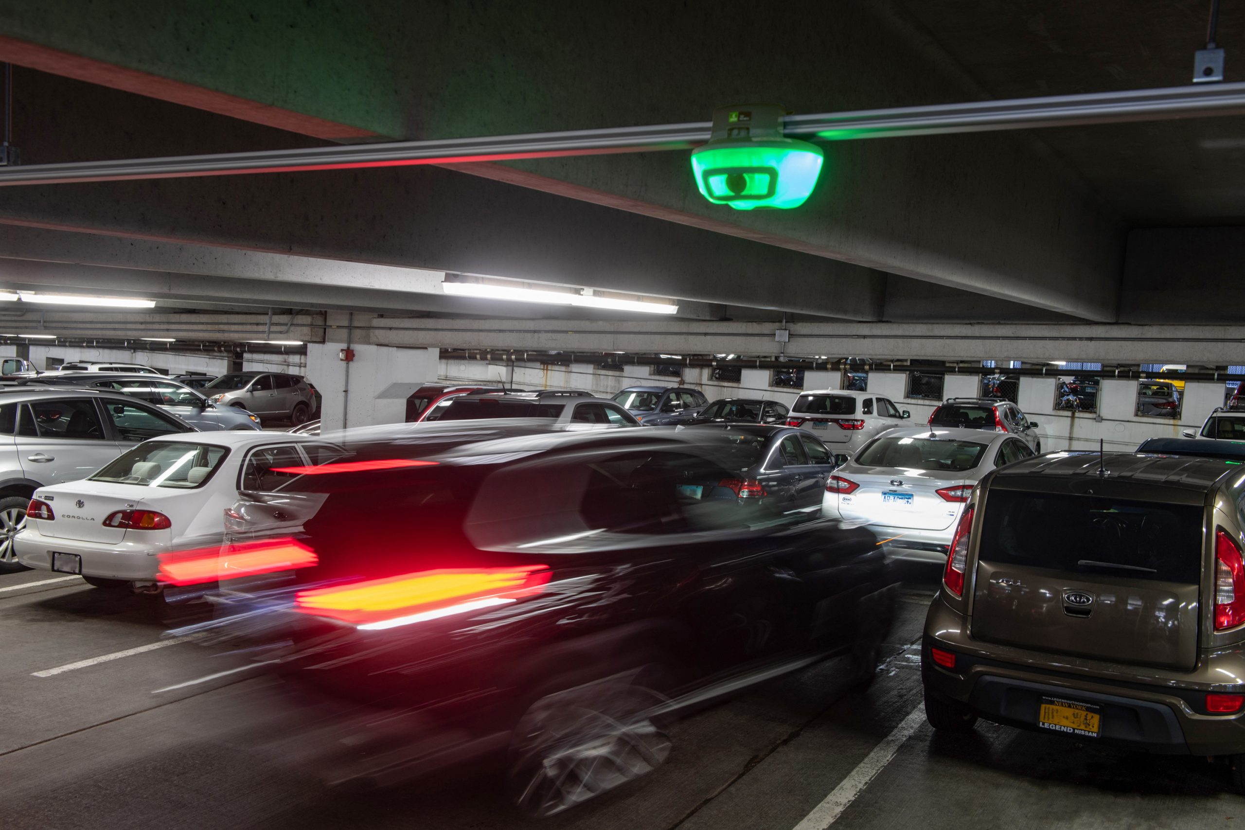 A close-up of a car parking under a Park Assist camera based M5 smart sensor in a parking garage.