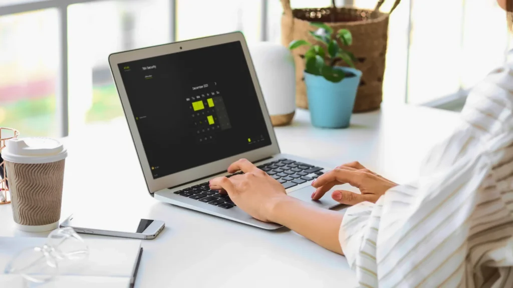 Person using a laptop with a calendar interface for ATLAS access control scheduling