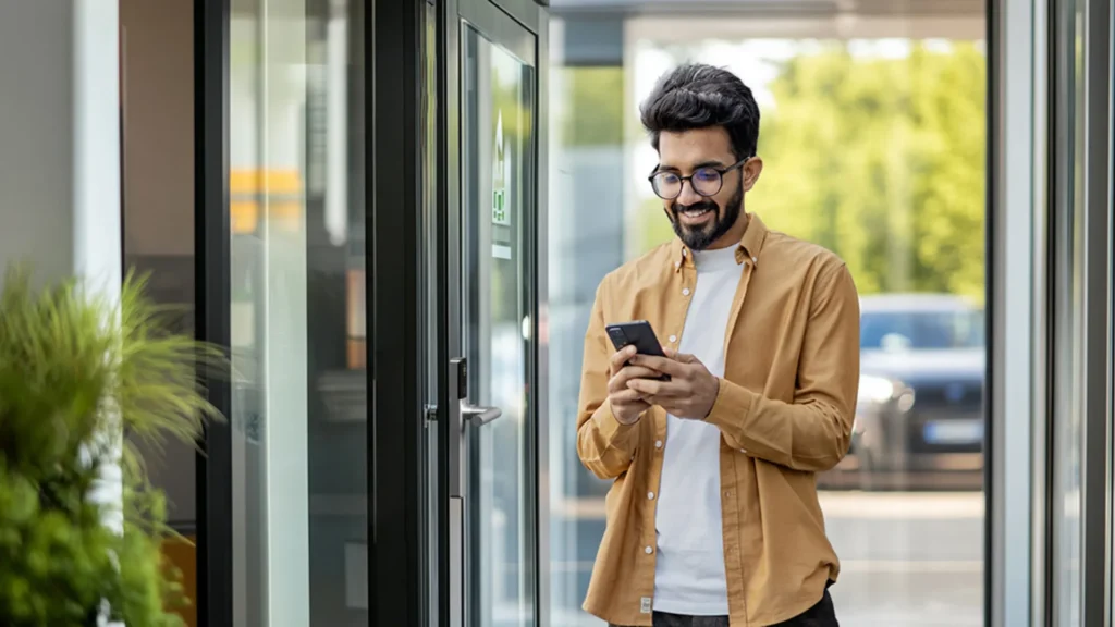 Man using a smartphone near a building entrance door with ATLAS access control system