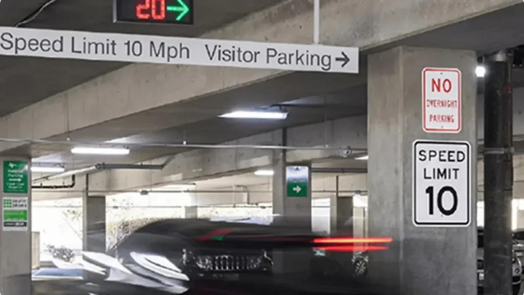 Car driving in UT Dallas parking garage under VMS sign showing 20 spaces available to the right