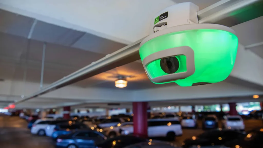 A green M5 smart sensor inside a parking garage, indicating an available parking space is nearby.