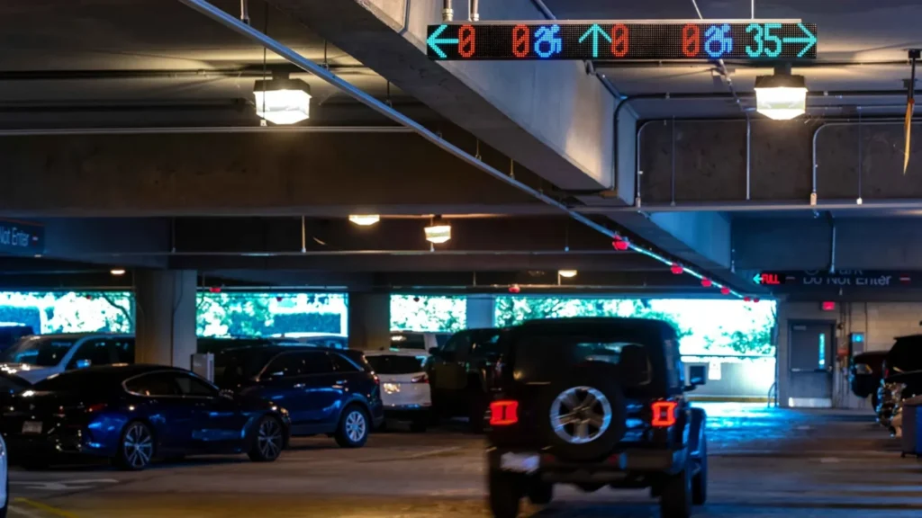 On the inside of a parking garage, a vehicle is using M5 smart sensors and VMS signage to locate somewhere to park.