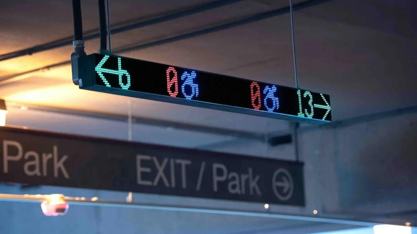 A VMS digital wayfinding sign inside a parking garage displaying available spaces to the left and to the right