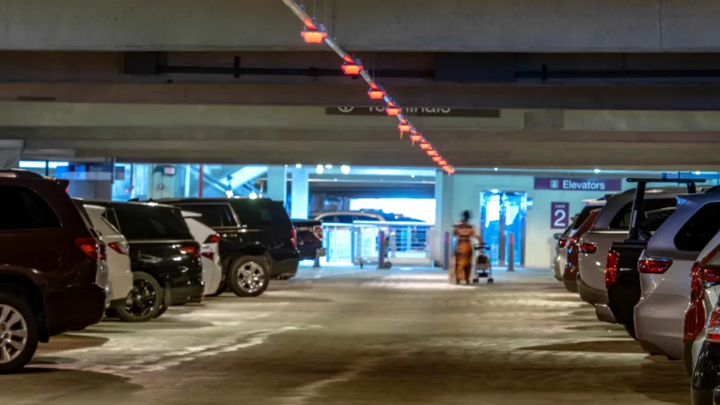 Full parking garage with red M5 smart sensors, from a parking guidance system, indicating occupied spaces and a person walking toward the elevator
