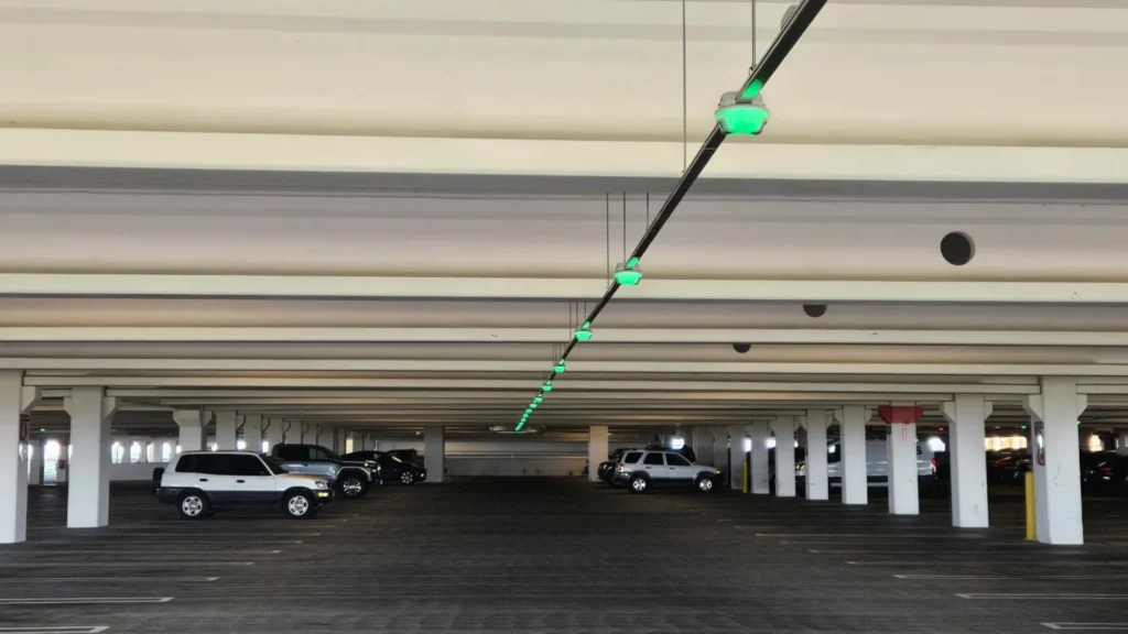 Mostly empty parking garage with a continuous row of green M5 parking guidance sensors, the heart of a Park Assist parking guidance system