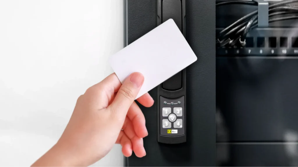 Hand holding an access card near a TKH Security swing handle and network switch panel