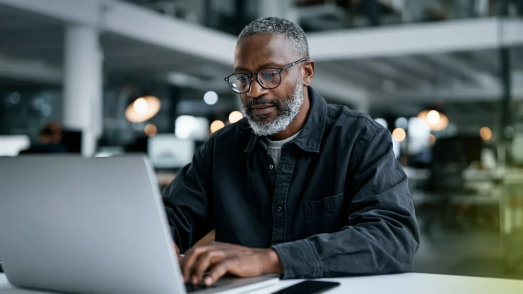 A facility manager working on a laptop in an open-plan office