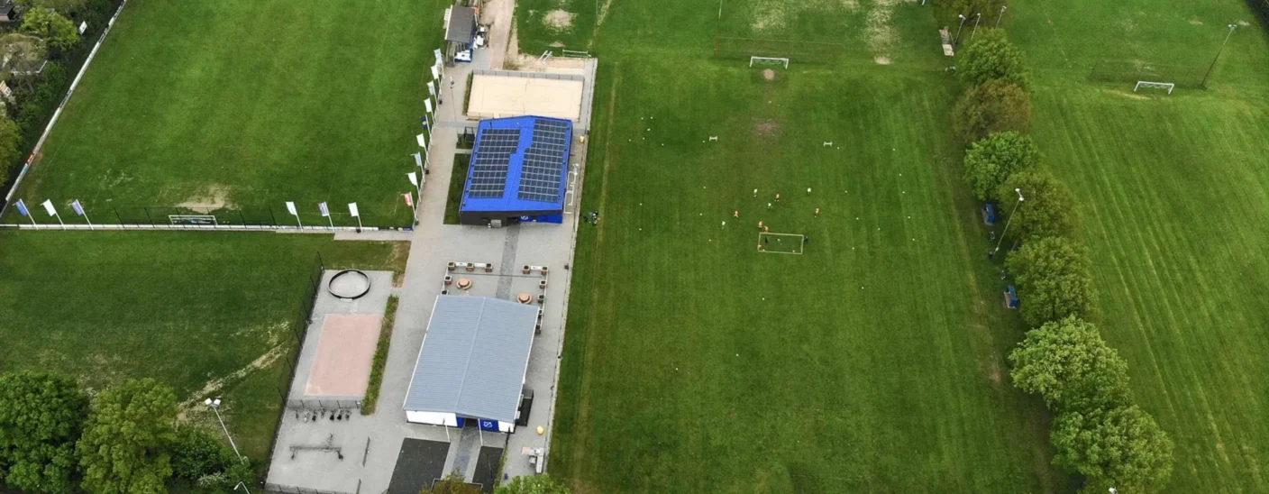 Aerial view of Angerlo Vooruit Football Club's sports fields and clubhouse, showing multiple pitches, solar panels, and training areas.